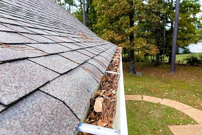 worker cleaning gutter on a residential house